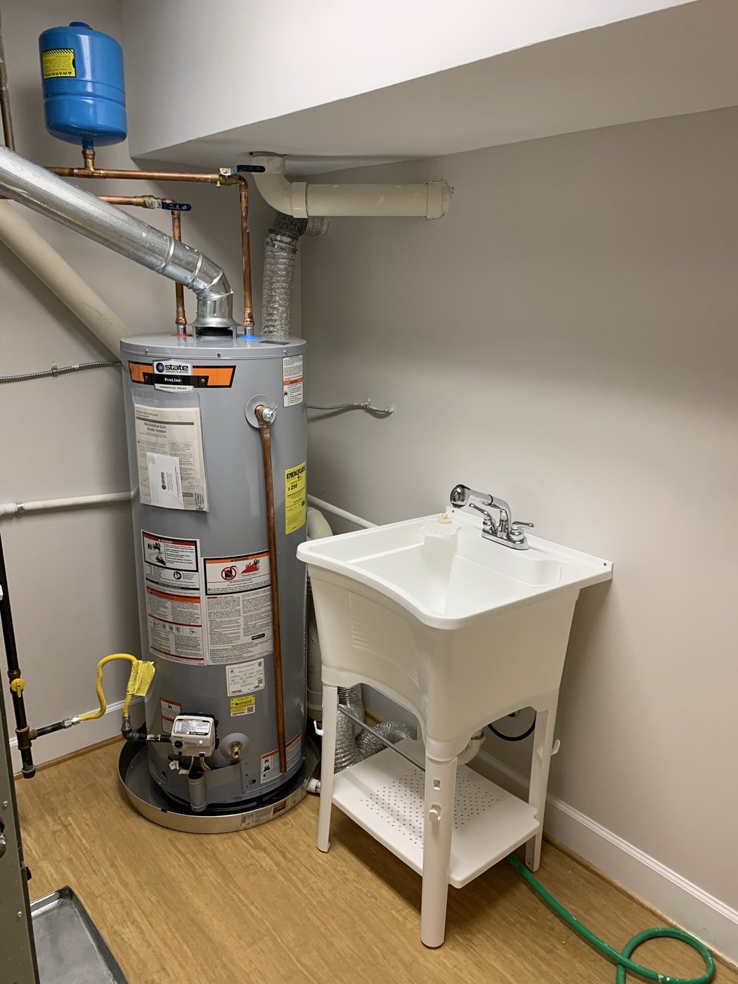Water heater installation near utility sink completed by Mercy's Plumbing